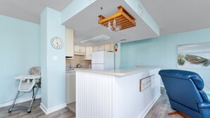 A kitchen with a white refrigerator, a wooden ceiling, and a clock on the wall. - 5611- King's Landing - Nags Head Coastal Condo Near The Beach (Nags Head)