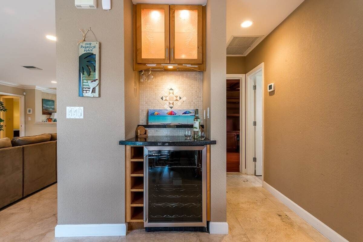 A compact kitchen with built-in cabinets, a wine cooler, and a backsplash with a geometric pattern.