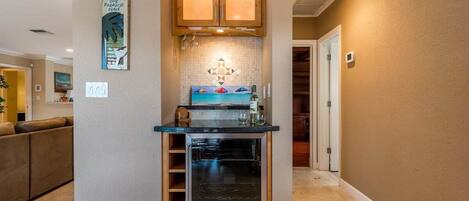 A compact kitchen with built-in cabinets, a wine cooler, and a backsplash with a geometric pattern.