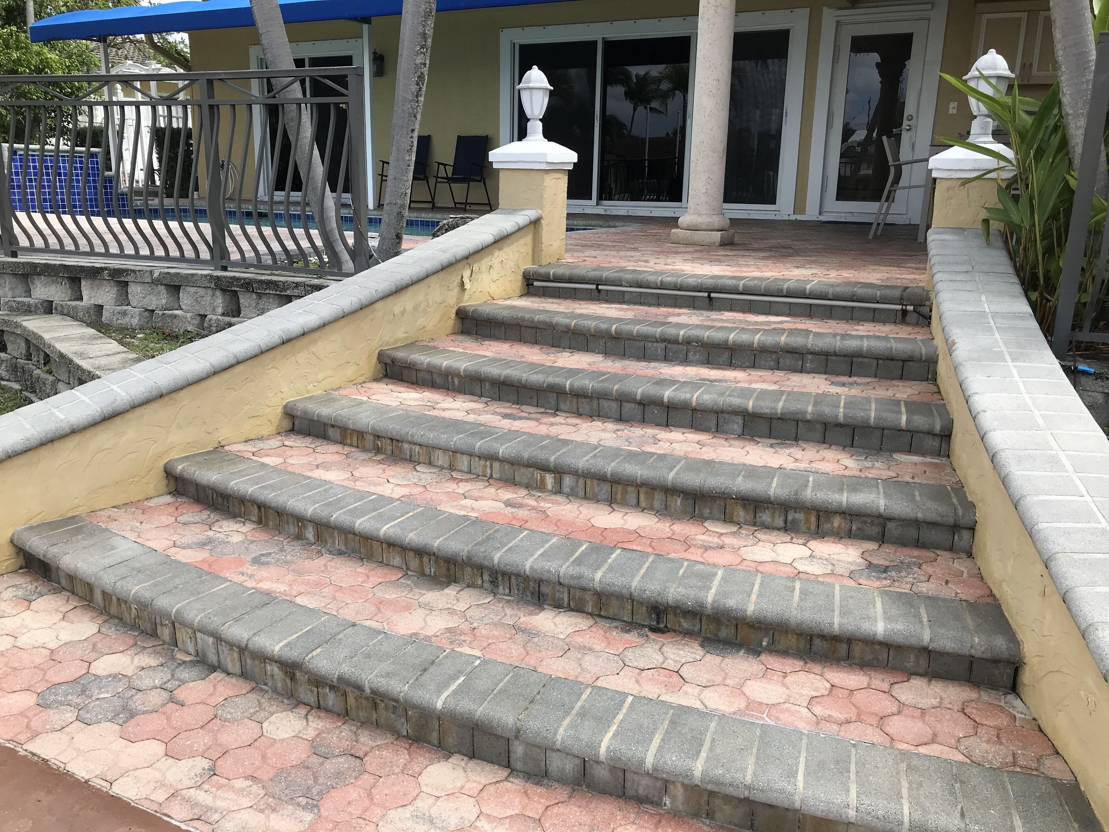Un conjunto de escalones de piedra al aire libre que conducen a la entrada de un edificio con toldo azul y una columna blanca.
