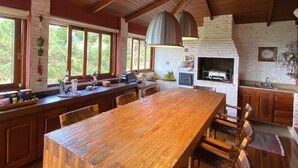 Eine geräumige Küche mit großem Holztisch, eingebauten Schränken und einem Steinkamin.