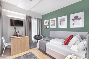 A modern hotel room with a bed, a desk, a chair, and artwork on the wall. - Myhome Munich (Munich)