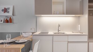 Eine moderne Küche mit integriertem Spülbecken, einem Essbereich mit Tisch und Stühlen sowie einem an der Wand befestigten Regal mit Dekorationselementen.
