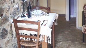 A dining area with a stone wall, a table set with plates, wine glasses, and a candle holder. - A cozy nest for a pair (Civitella Paganico)