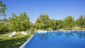 A swimming pool with clear blue water, surrounded by green grass and trees. - A cozy nest for a pair (Civitella Paganico)