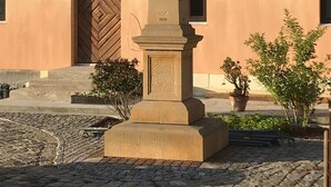 A building with a large wooden door and windows, a stone monument with inscriptions, and a street lamp. - Child-friendly holiday home NAMIBIA-LODGE in the Leppersdorf manor (Wachau OT Leppersdorf)