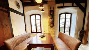 A room with a wooden table and two leather benches. There are two windows with wooden frames and a stone wall with a decorative mask. - Child-friendly holiday home NAMIBIA-LODGE in the Leppersdorf manor (Wachau OT Leppersdorf)