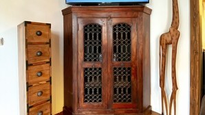 A room with a wooden cabinet with drawers, a television on top, and a giraffe statue. - Child-friendly holiday home NAMIBIA-LODGE in the Leppersdorf manor (Wachau OT Leppersdorf)