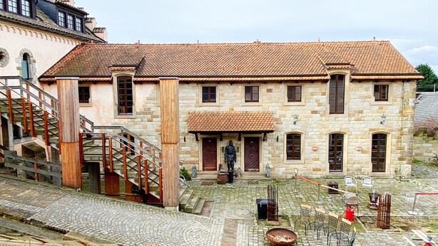 A stone building with a tiled roof, a staircase, and outdoor seating. - Child-friendly holiday home NAMIBIA-LODGE in the Leppersdorf manor (Wachau OT Leppersdorf)