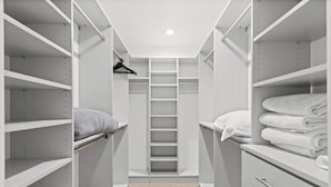 Un dressing accessible sans porte, doté d’étagères ouvertes, d’une tringle à vêtements et d’un porte-serviettes pliable.