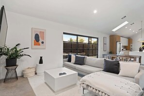 Ein modernes Wohnzimmer mit einer Couch, einem Couchtisch und einem großen Fenster.