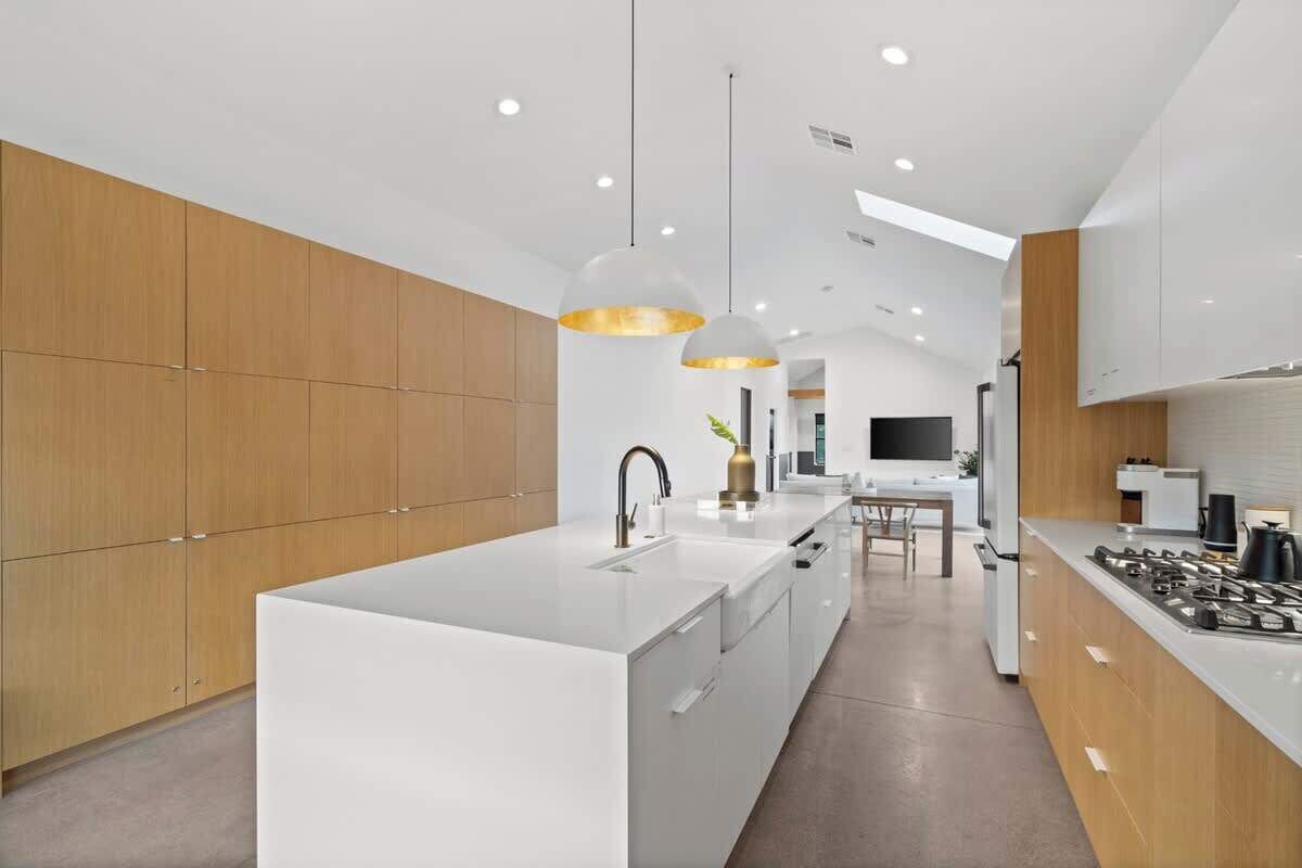 A modern kitchen with a central island, pendant lighting, and wooden cabinetry.
