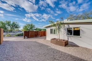 A single-story building with a white exterior, a small window, and a wooden fence in the background. - Tucson Spring Street (right unit) · New!|Chic Duplex in Tucson||UofA|1 of 2 (Tucson)