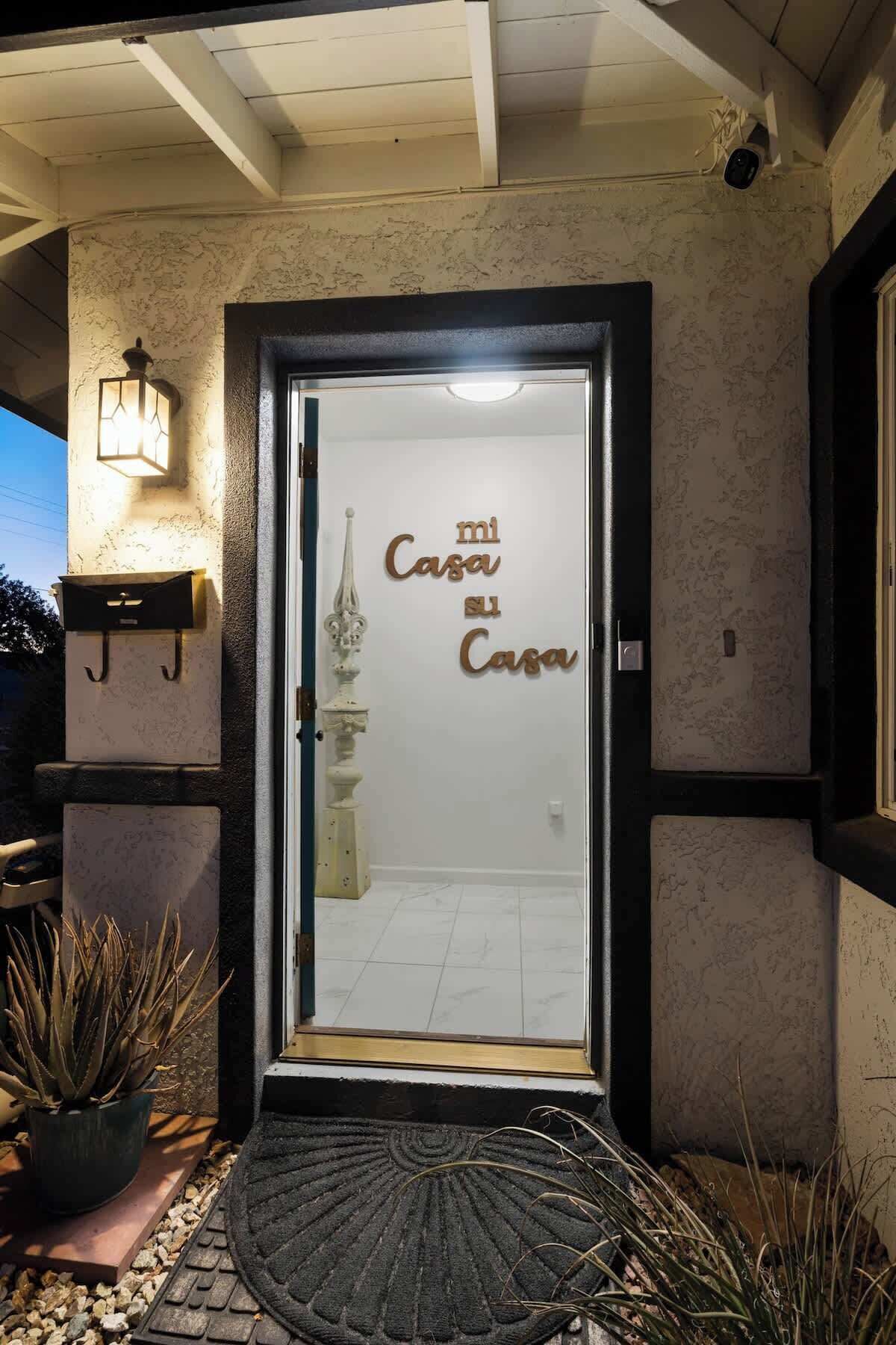 A hotel entrance with a glass door, a decorative metal gate, and a potted plant.