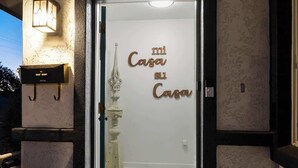 Entrada de un hotel con puerta de vidrio, una reja decorativa y una planta en maceta.