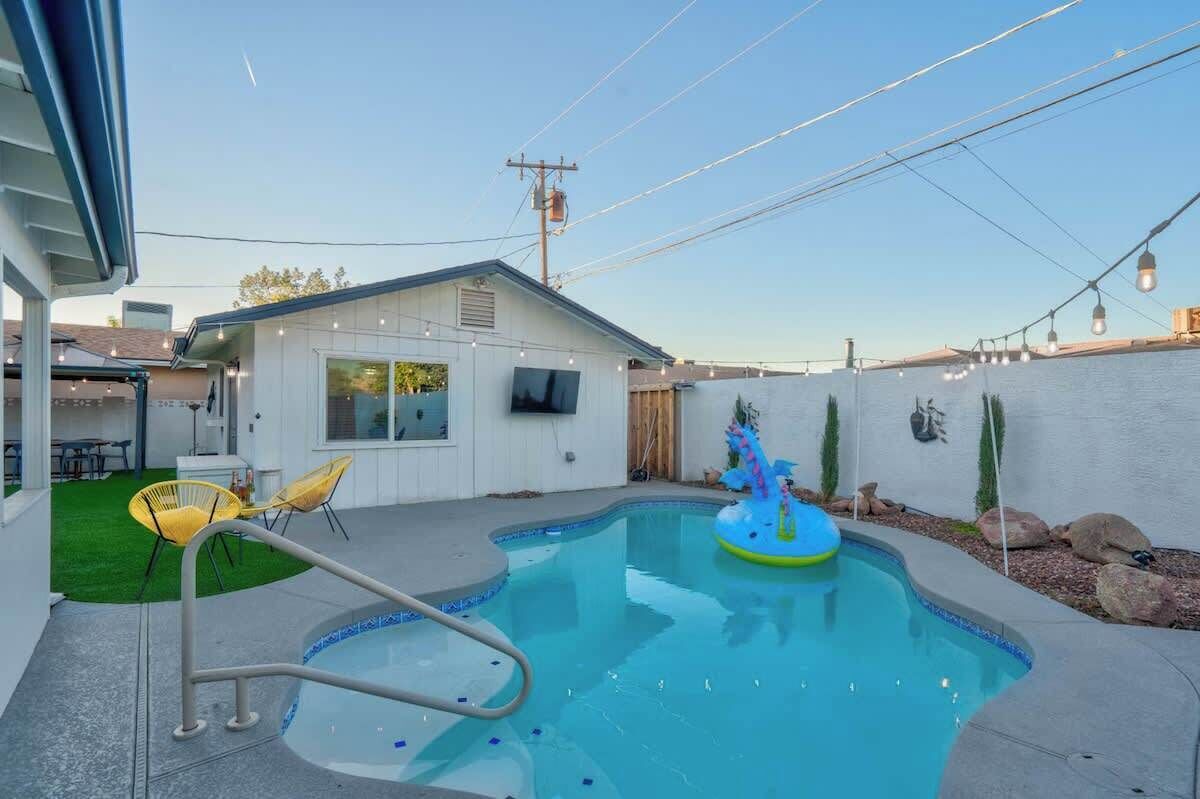 Un patio trasero con piscina, jacuzzi y un pequeño flotador inflable.