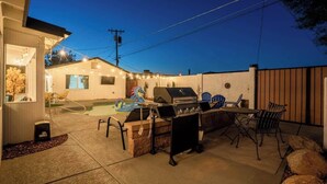 Un área de patio al aire libre con una parrilla, asientos y una piscina.