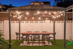 A covered patio with a table and chairs, surrounded by a white wall with decorative patterns.