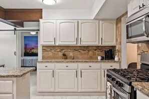 A kitchen with white cabinets, a gas stove, and a microwave. - BOHO Scottsdale Oasis | Pool (Scottsdale)