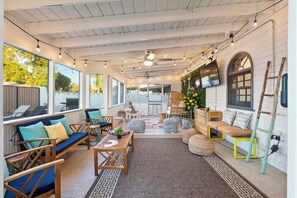 An indoor patio area with seating arrangements, a television, and a decorative wall.