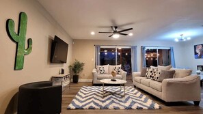 A living room with a ceiling fan, two sofas, a coffee table, and a large cactus decoration.