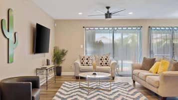 A living room with a sofa, a coffee table, a TV, and a cactus decoration.