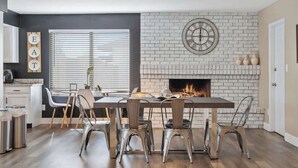 Une cuisine moderne avec une cheminée, une table à manger avec des chaises et un panneau « À MANGER » accroché au mur.