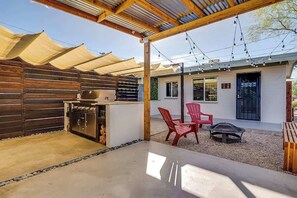 Un espace extérieur aménagé avec une terrasse, un barbecue, des sièges et une pergola.