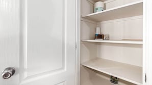 A white door with a silver handle, adjacent to a white wall with three empty shelves.