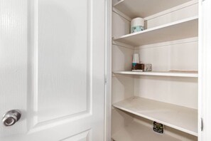 A white door with a silver handle, adjacent to a white wall with three empty shelves.