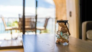 Un frasco de vidrio transparente con tapa sobre una mesa de madera, que contiene pequeños adornos y un hilo.