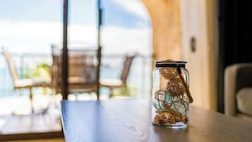 Een transparante glazen pot met deksel op een houten tafel, gevuld met kleine decoratieve objecten en een touwtje.