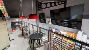 Een bar met krukken, een toonbank met hapjes en een televisiescherm.