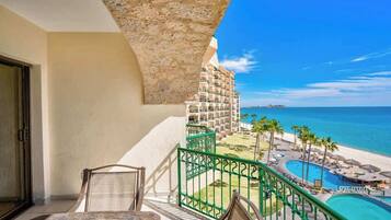 Ein Balkon mit Blick auf Strand und Pool, ausgestattet mit einem Stuhl und einem Tisch.