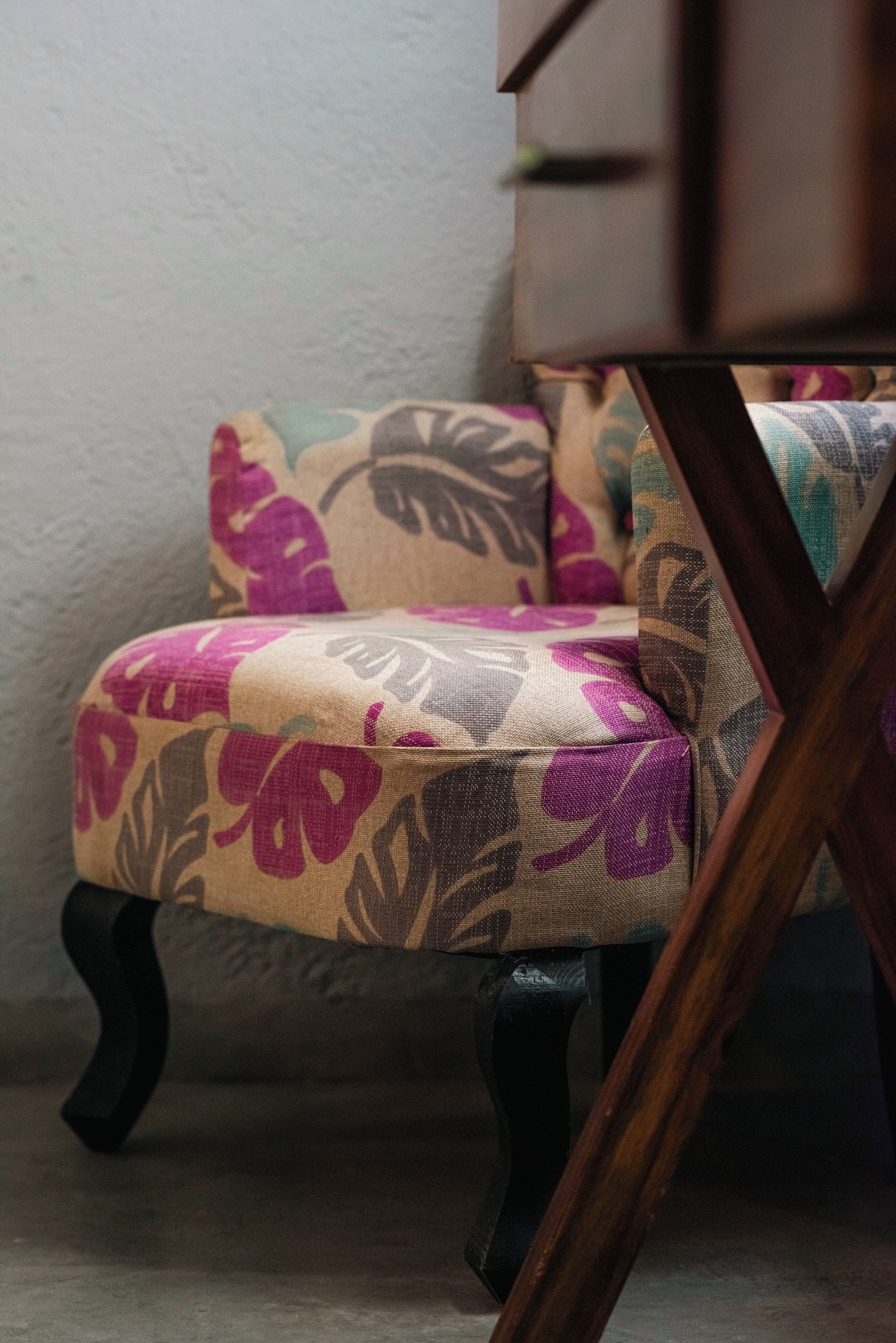 Une chaise ornée d’un motif floral, placée contre un mur dont la surface est texturée.