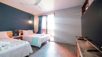 Un dormitorio con dos camas, un ventilador de techo, una mesita de noche, un aparador y una ventana con cortinas.