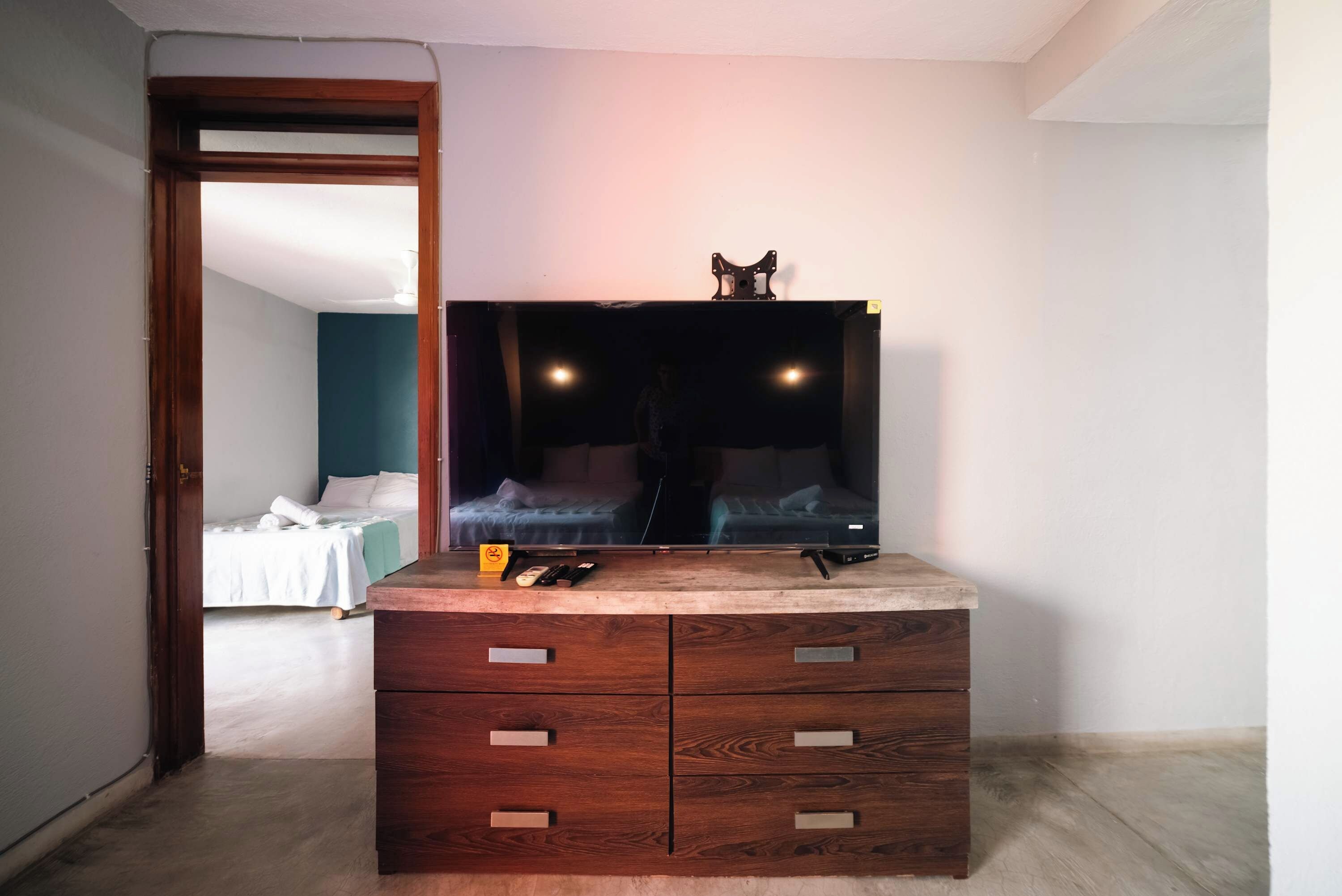 Un aparador de madera con cajones, un espejo y una mesita con objetos encima.