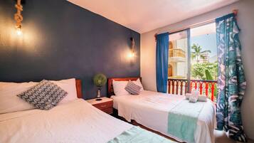 A hotel room with two beds, a nightstand with a lamp, a window with curtains, and a balcony with a railing.