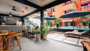 A reception area with a desk, chairs, and a reception sign. There is a pool area with lounge chairs and umbrellas. - Zihua Mia Hotel Boutique 5 (Zihuatanejo)