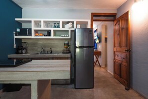Eine Küche mit Kühlschrank, Mikrowelle und Regalen voller Küchenutensilien.