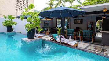 A pool area with lounge chairs, umbrellas, and potted plants.