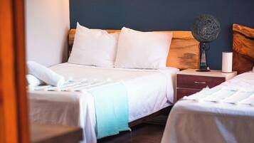 Una habitación de hotel con dos camas, una mesita de noche, una lámpara y otra mesita auxiliar.