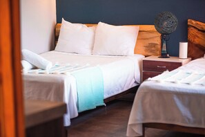 Ein Hotelzimmer mit zwei Betten, einem Nachttisch, einer Lampe und einem Beistelltisch.