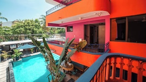 Un immeuble à plusieurs étages doté d’une piscine, de balcons et d’un espace extérieur aménagé pour s’asseoir.