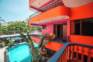Ein mehrstöckiges Gebäude mit Swimmingpool, Balkonen und Außenbereich zum Sitzen.