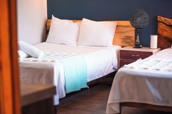 A hotel room with two beds, a bedside table, a lamp, and a nightstand.