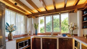 Une cuisine avec des poutres en bois, un four à micro-ondes encastré et une fenêtre donnant sur un paysage verdoyant.