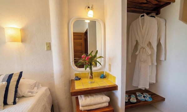 Ein Badezimmer mit Spiegel, Waschbecken, Handtuchhalter und Ablage mit Hausschuhen.