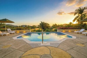 Ein Poolbereich mit Liegestühlen und Blick auf den Sonnenuntergang.
