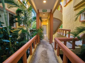 A corridor with a staircase, surrounded by greenery, leading to a door marked 'EXIT OF PRESSURE.' - Villa Bougainvillea at Villas del Sol (Zihuatanejo)